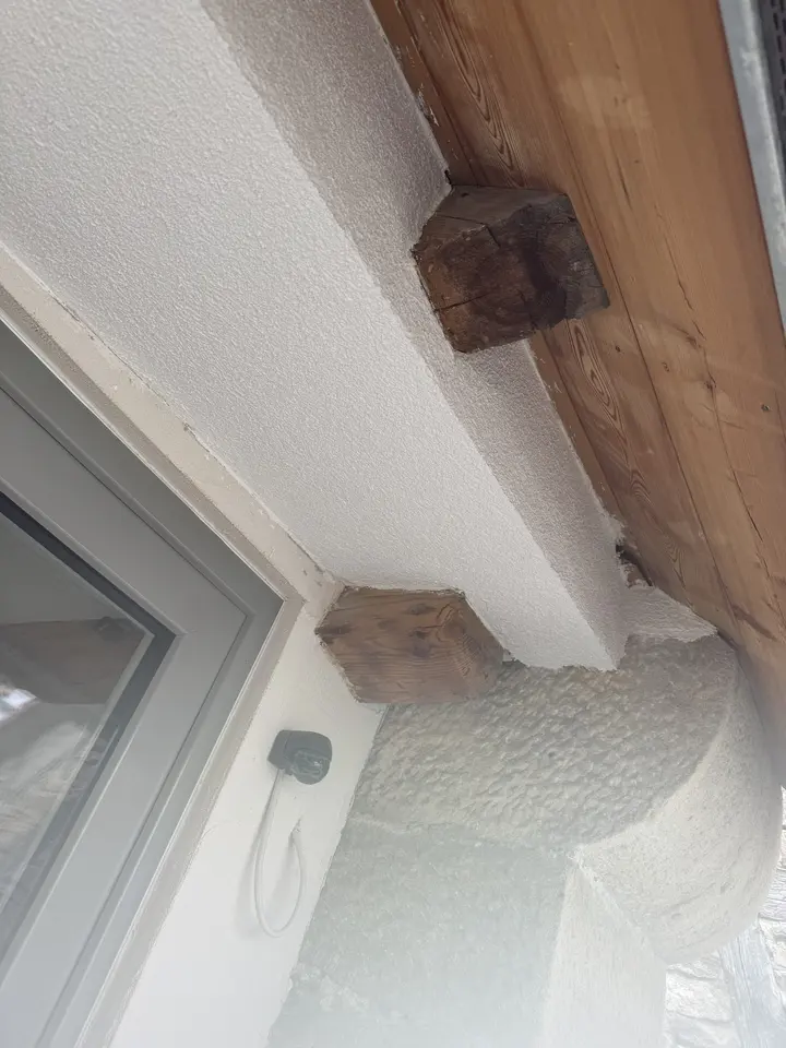 Detail einer Fensterlaibung: Putzanschluss an einen freigelegten historischen Deckenbalken