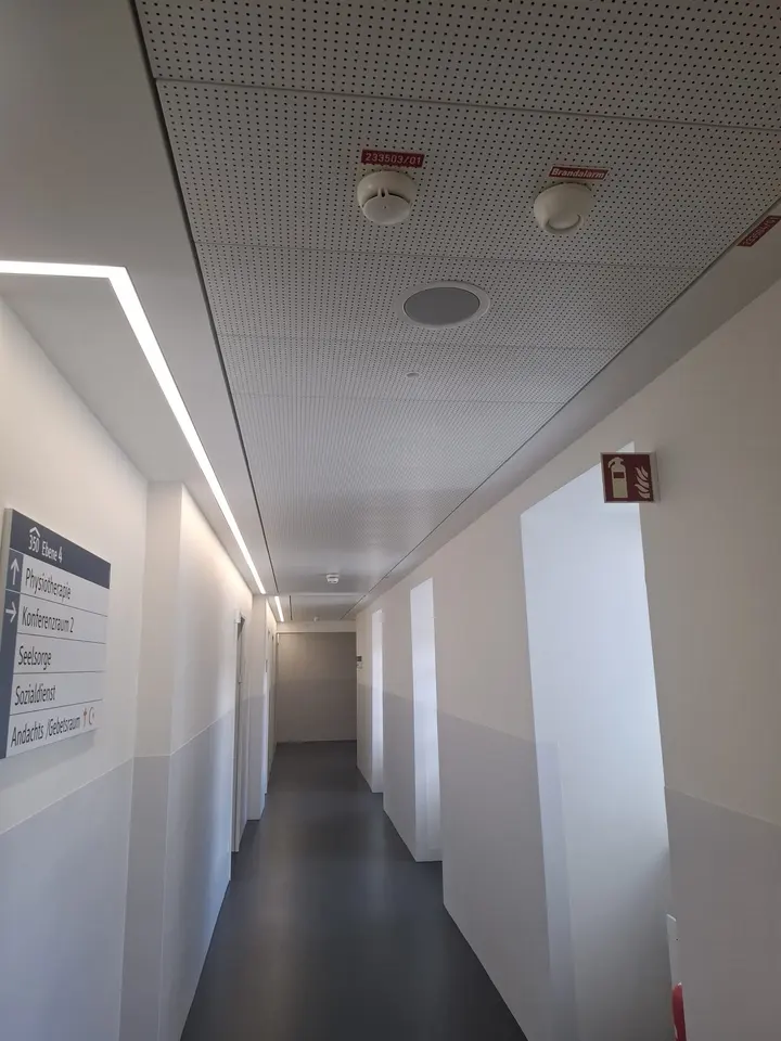 Flur mit abgehängter Akustikdecke, umlaufendem Lichtband und Wegeleitsystem