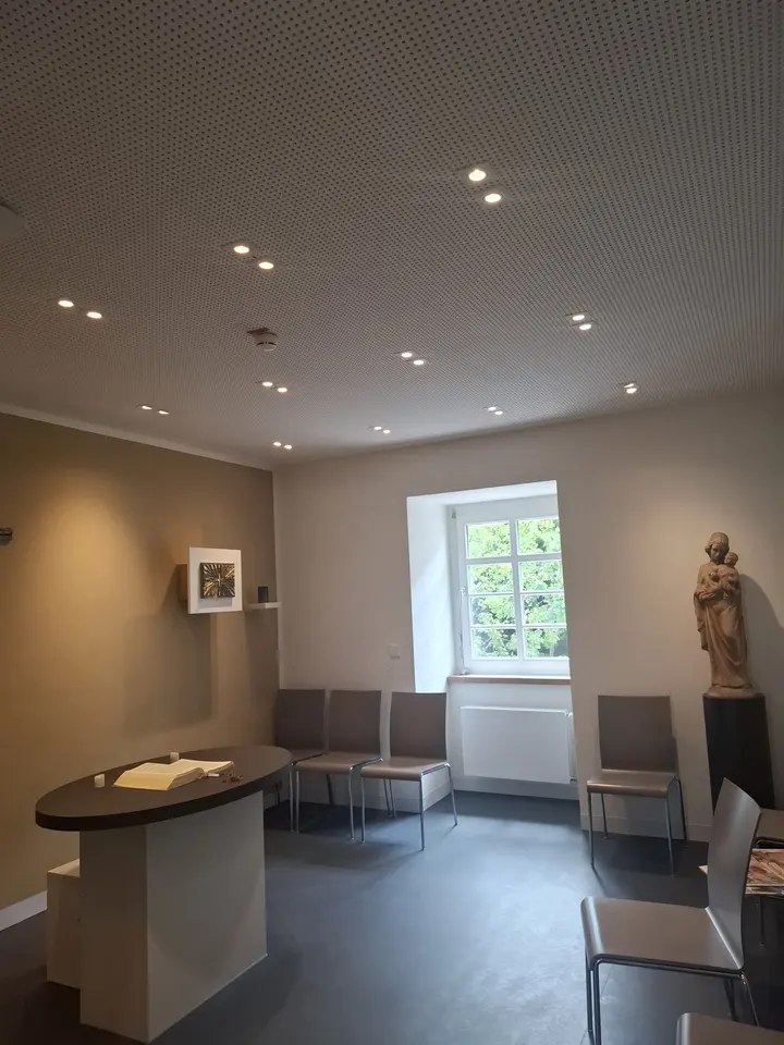 Aufenthaltsraum mit Akustikdecke, Einbauspots und Sitzgruppe am Fenster