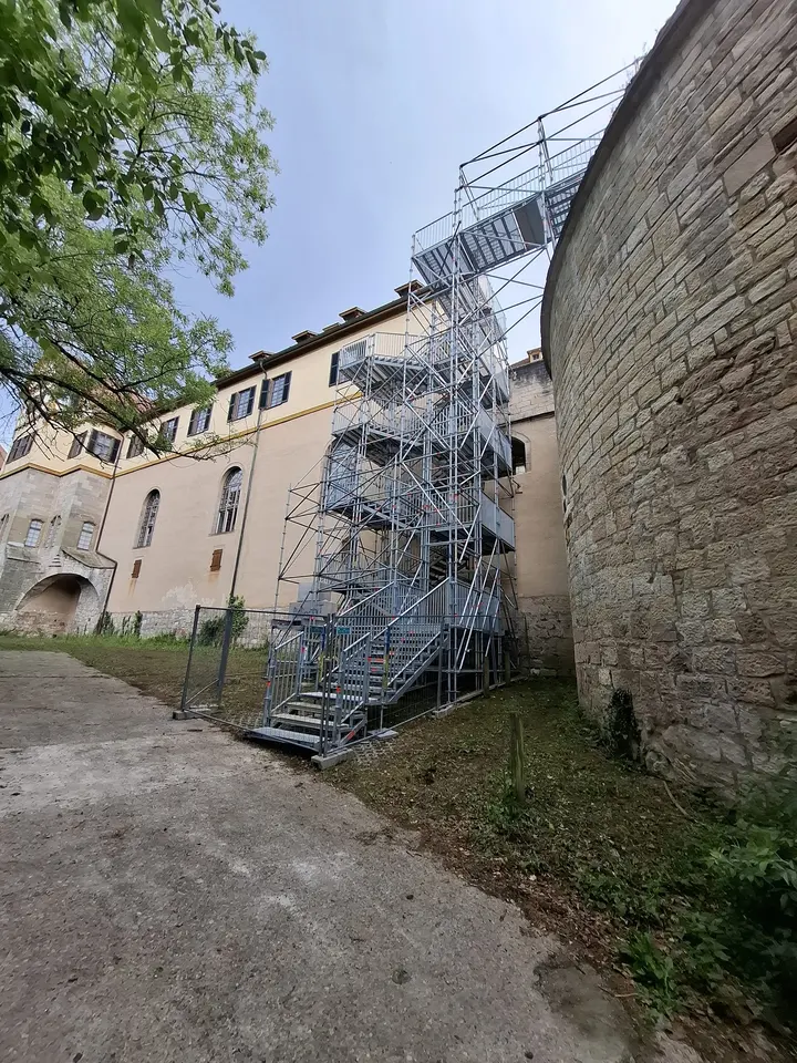 Gerüsttreppenturm entlang einer historischen Bruchsteinmauer als Zugang zum Obergeschoss