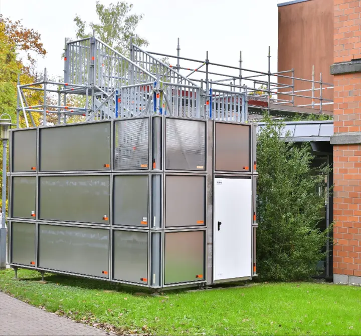 Wetterfeste Einhausung aus Gerüstbauteilen mit verschließbarer Tür